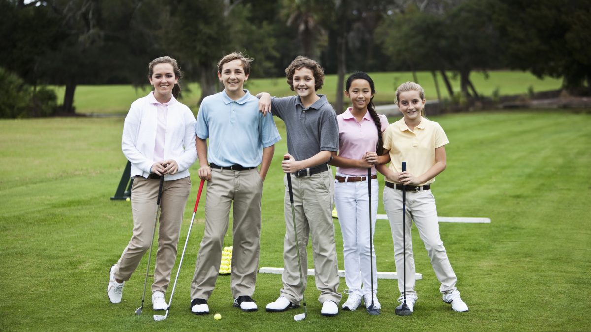 Juniors on the golf driving range, taking golf clinic.